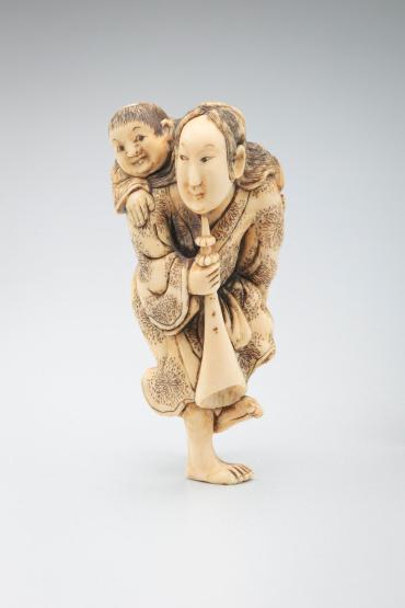 Netsuke: woman with child and trumpet