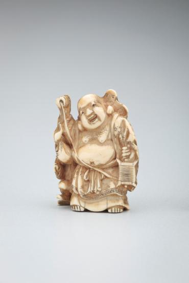 Netsuke: Hotei, with a boy, holding a kite