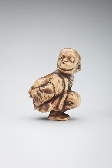 Netsuke: crouching boy wearing a mask