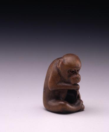 Netsuke: seated monkey biting its hand