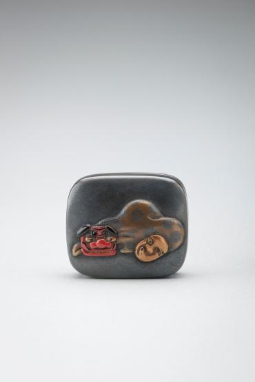 Netsuke: lacquer box with two New Year's masks on cover