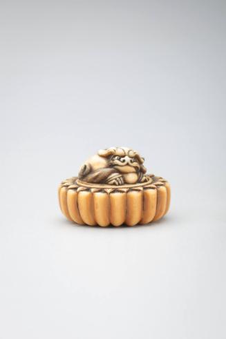 Netsuke:  recumbant lion with a ball on a lotus form