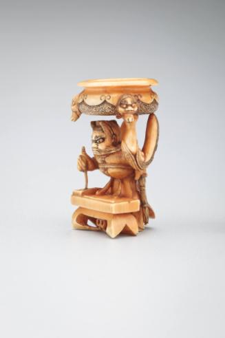 Netsuke: Goshisho holding bronze cauldron while writing a poem