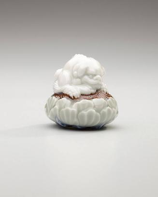 Netsuke: crouching shishi lion on a lotus pedestal