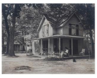 View of Cottage with Woman Seated in Rocker on Porch